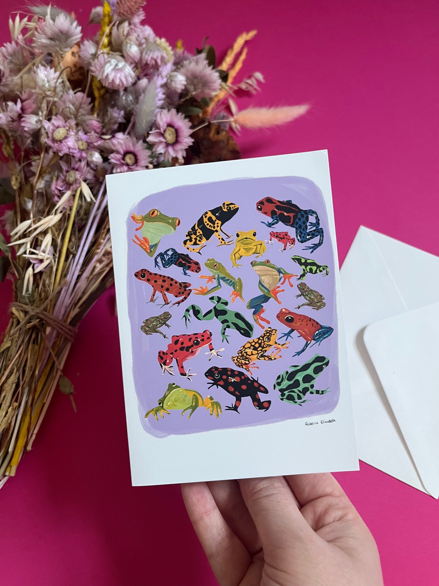 A collection of vibrant froggies to bring a pop of colour to your life. Hand painted rainforest frogs in gouache and edited digitally into a collaged design on a purple background with a pink back and the Rebecca Elizabeth Draws logo.