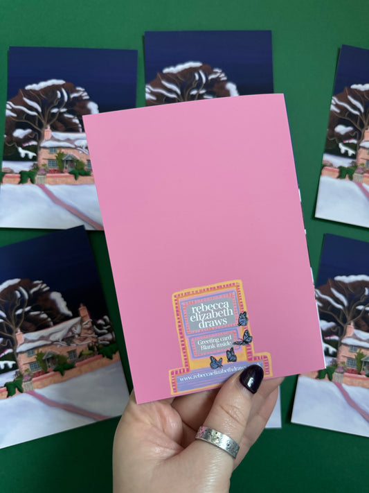 Christmas Illustration of the classic Rosehill cottage from the movie The holiday staring Kate Winslet and Cameron Diaz. Set amongst the English countryside with landscapes of wintery fields, a classic cosy Christmas cottage. Christmas card with pink back designed by Rebecca Gibbs at Rebecca Elizabeth Draws.