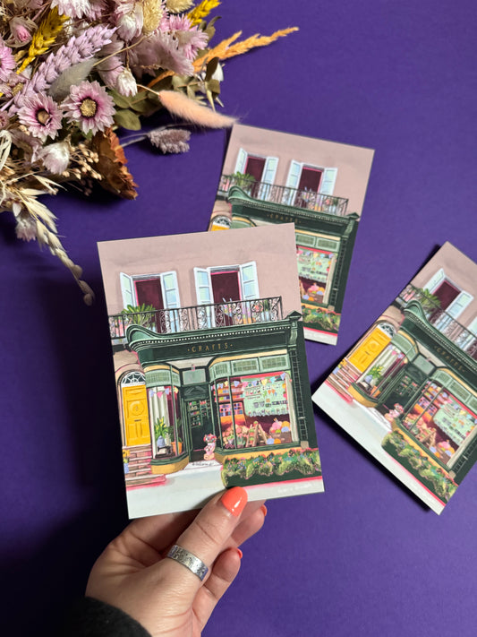 A colourful illustration of a craft shop with the store front in green and looking through the window and at all the goodies. Sewing, drawing, painting, we have it all here at the craft shop. Designed by Rebecca Elizabeth draws.