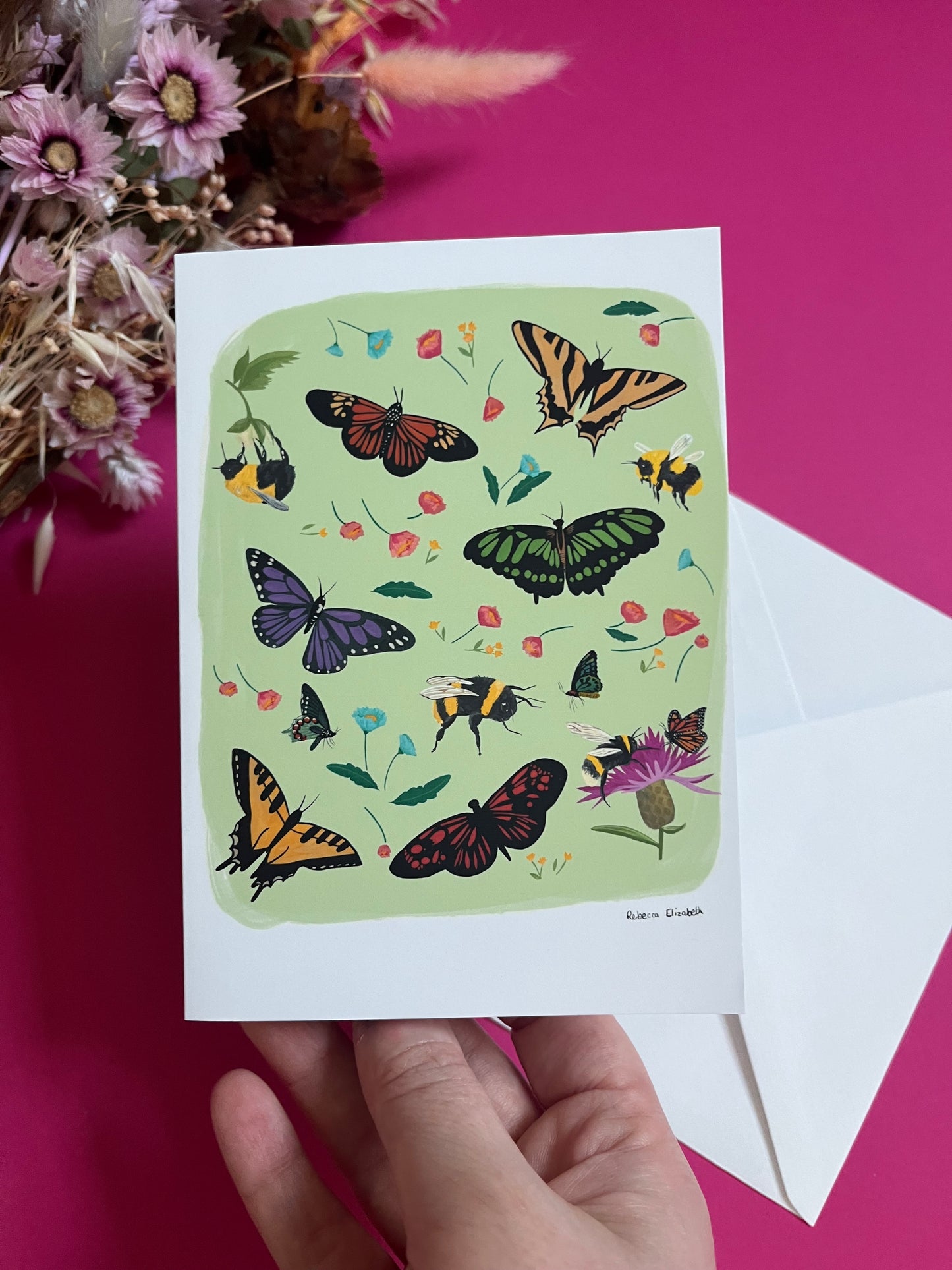 A collection of wildflowers, bumblebees and butterflies hand painted in gouache and edited digitally into a collaged design on a light green background. With a green back and the Rebecca Elizabeth Draws logo.