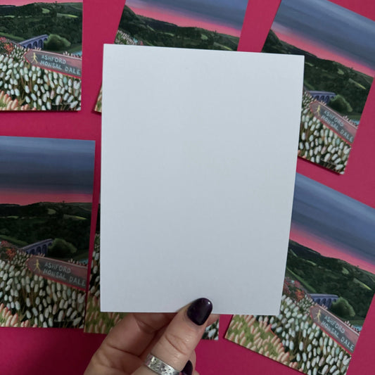 Postcard art of Monsal Head in Derbyshire, Peak District. Rolling green hills filled with trees, an old viaduct over the river Wye and white flowers in the foreground. The sky is a setting sun with pink on the horizon fading into dark blue grey.