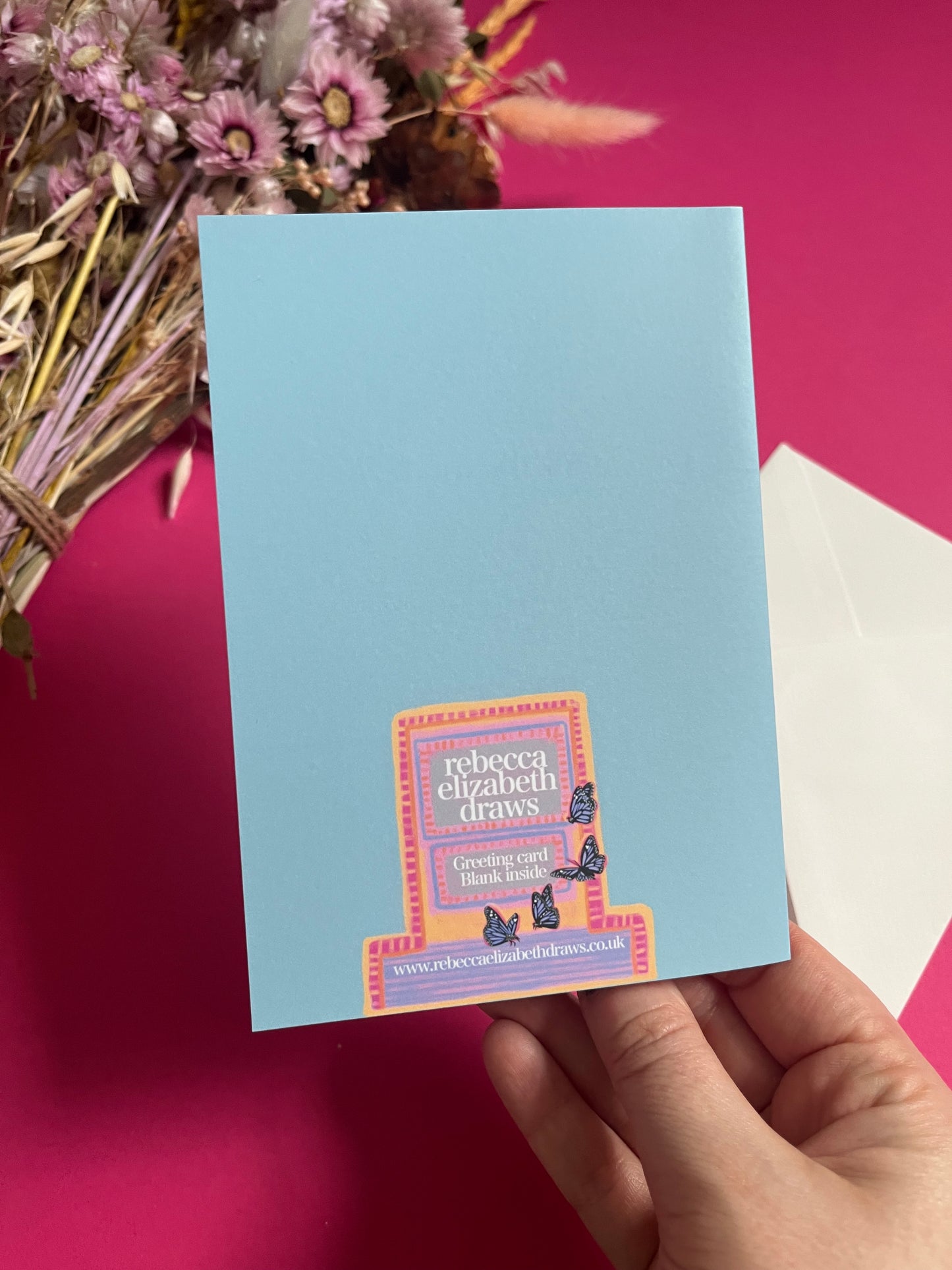 Cat illustrations in a collection on a colourful pink background with a small signature at the bottom. Blue background with lighter blue vertical stripes and a pink horizontal stripe along the top & bottom. The back is blue with the Rebecca Elizabeth draws logo.