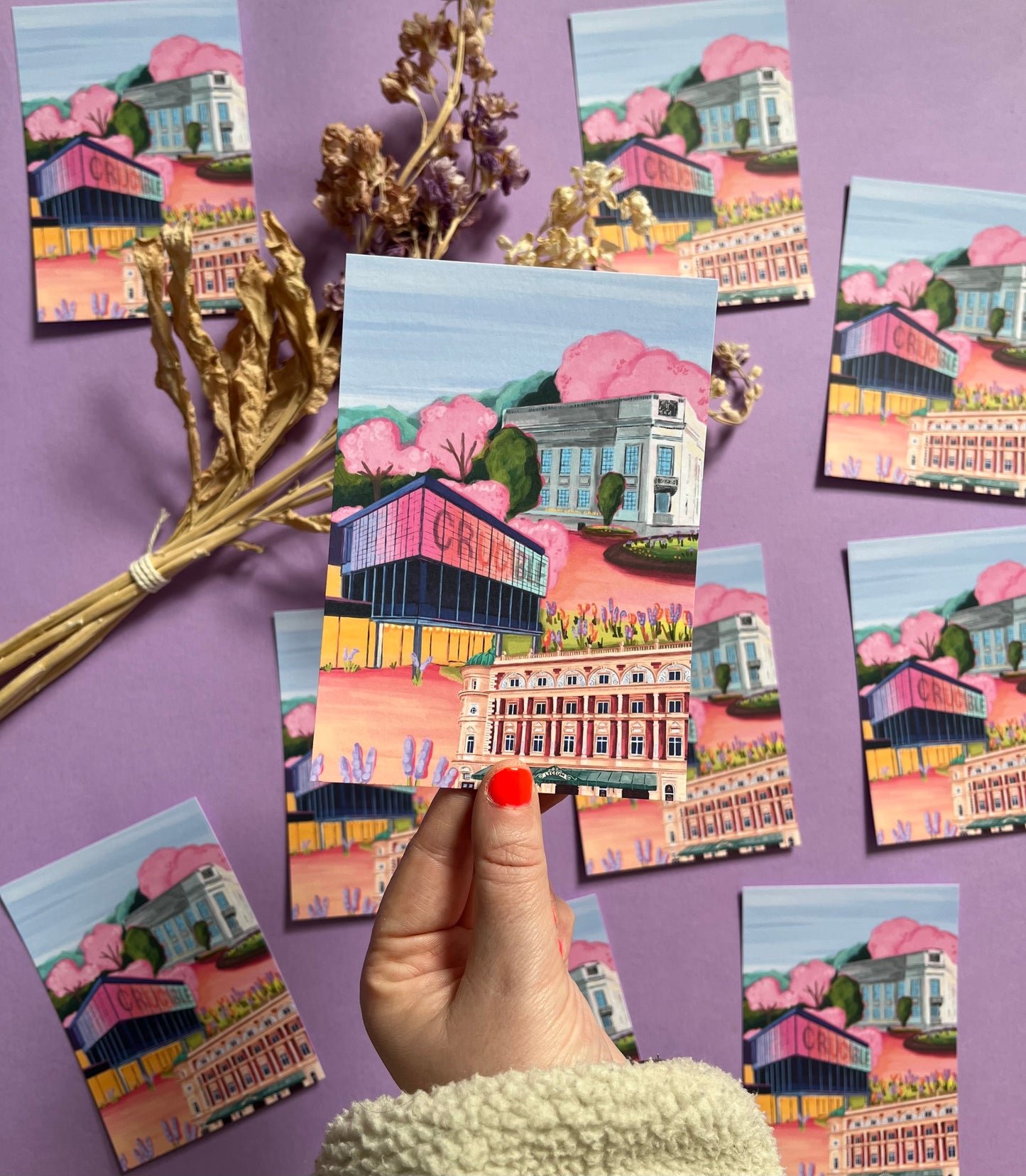 Sheffield theatres illustration, Crucible and Lyceum theatre are illustrated alongside Sheffield library on a background of pink and orange. Trees in both green and pink surround and a baby blue sky. Now available in a cute postcard designed at Rebecca Elizabeth draws.