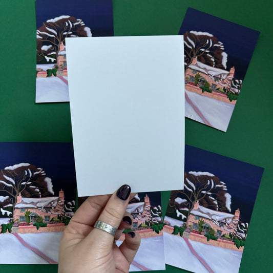 Christmas Illustrated postcard of the classic Rosehill cottage from the movie The holiday staring Kate Winslet and Cameron Diaz. Set amongst the English countryside with landscapes of wintery fields, a classic cosy Christmas cottage. Designed by Rebecca Gibbs at Rebecca Elizabeth Draws.