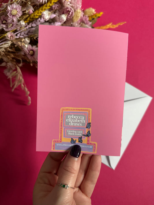 A coffee shop illustrated card with a blue exterior, an outside table and umbrella and building windows surrounding. This illustration is filled with lots of plants and flowers and features cups of coffee and baked goods. Illustrated by Rebecca Elizabeth Draws.