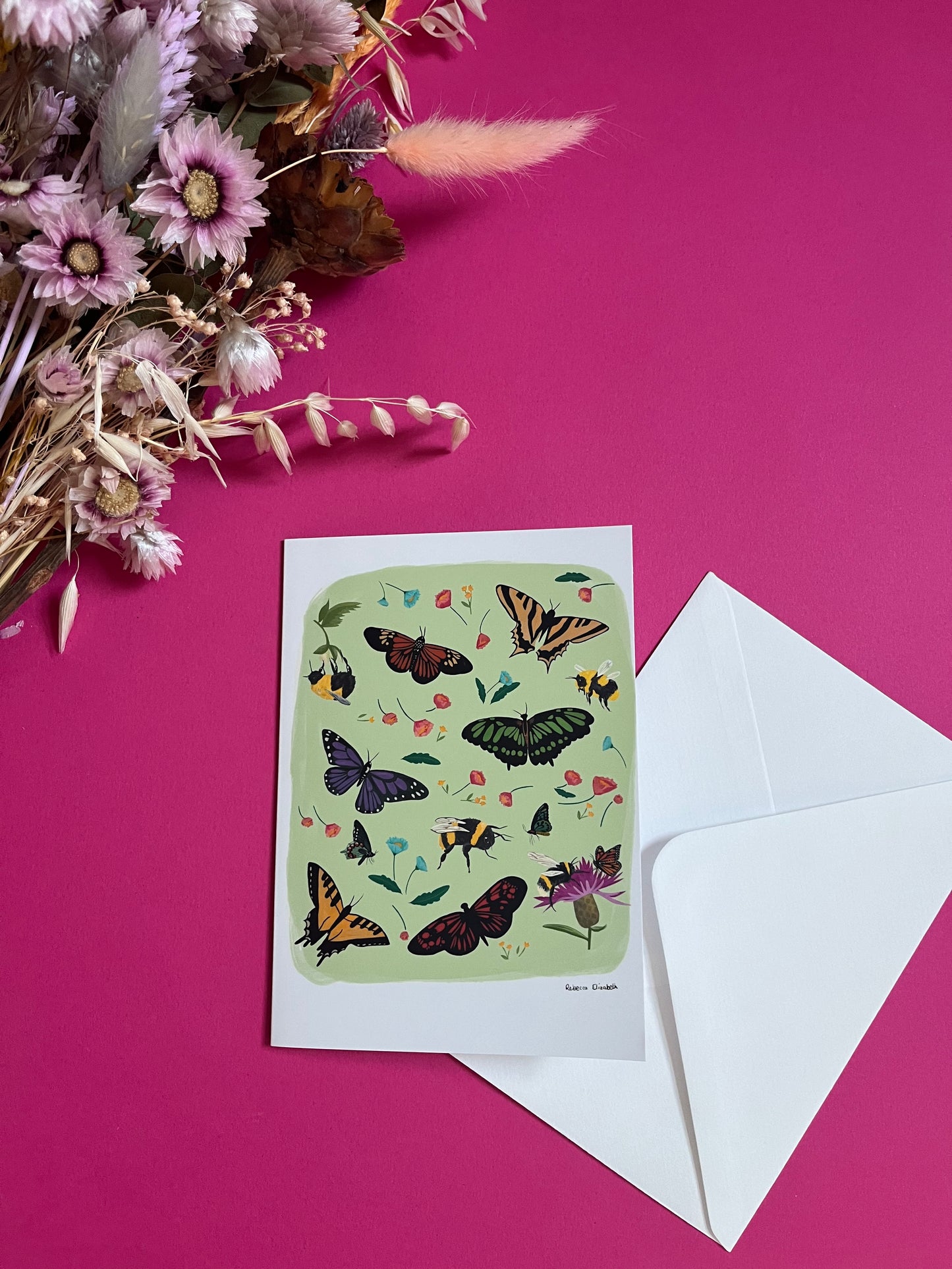 A collection of wildflowers, bumblebees and butterflies hand painted in gouache and edited digitally into a collaged design on a light green background. With a green back and the Rebecca Elizabeth Draws logo.