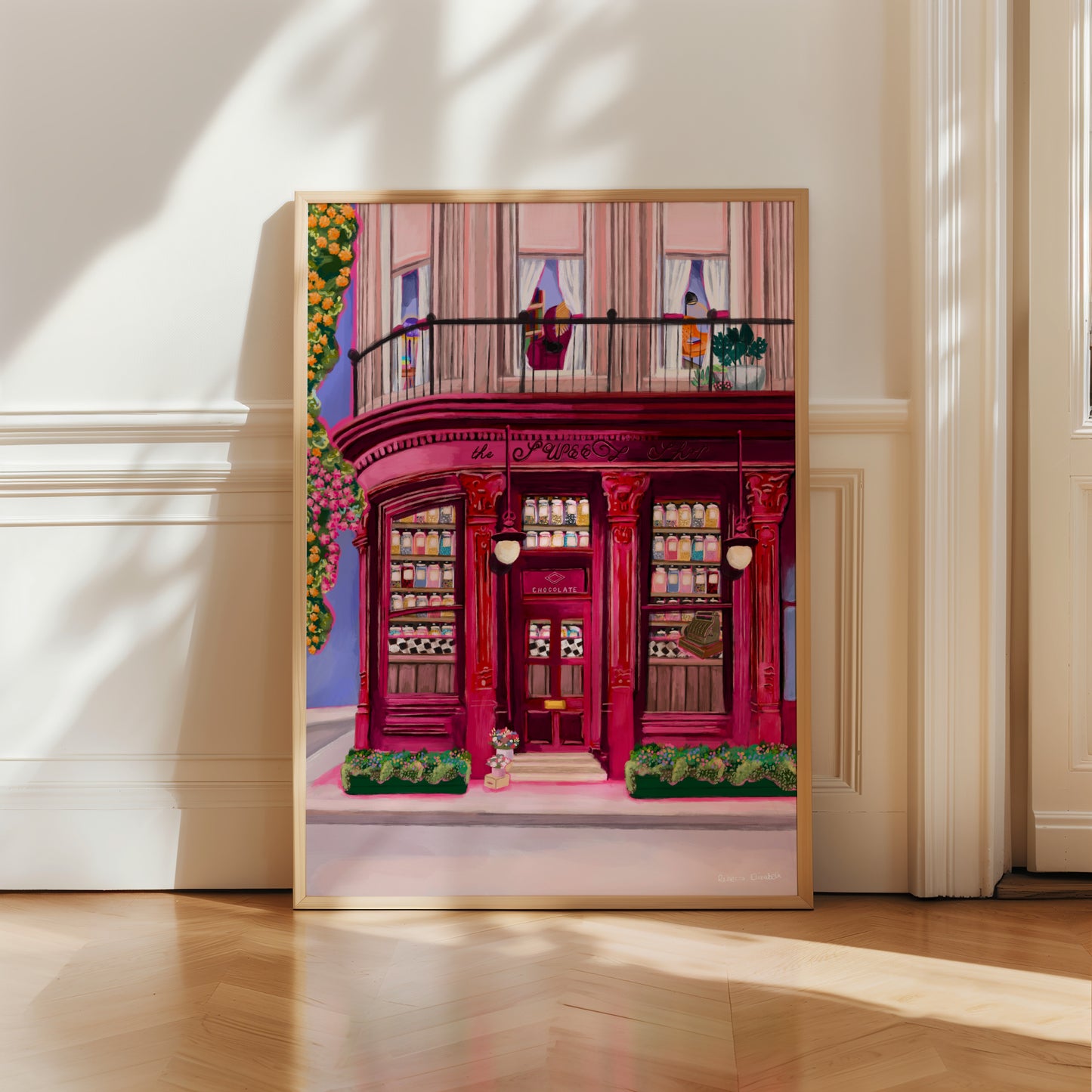 The sweet shop store front illustration. A red, burgundy, and pink toned shop front with ornate features, inside the window shelves of old-fashioned sweet jars filled with colourful candy. The countertop is black and white checker and a vintage till. The outside is surrounded by flowers. Designed by Rebecca Elizabeth Draws.