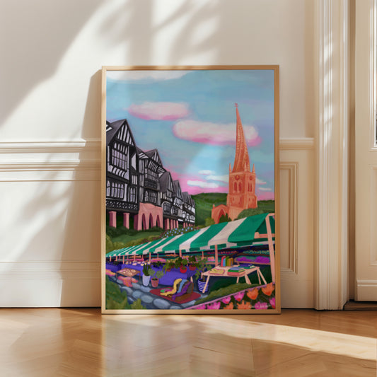 An illustration of the Derbyshire town Chesterfield. A summer illustration featuring the famous crooked spire, market stalls and Tudor buildings. Soft blue sky with fluffy clouds, this art piece is a soft representation of the market town. A small signature in white the corner. Designed by Rebecca Gibbs at Rebecca Elizabeth Draws.