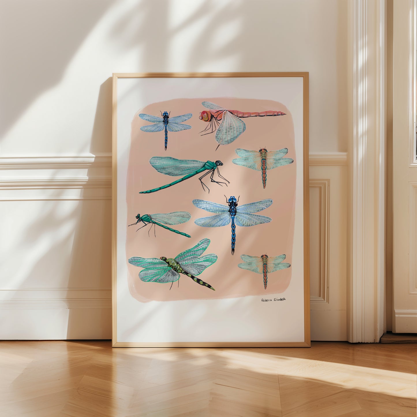 Hand painted dragonflies in gouache and edited digitally onto soft coloured cream backgrounds. Dragonflies in a flat lay composition with lots of intricate details featured. There is a small signature in black at the right. Designed by Rebecca Gibbs at Rebecca Elizabeth Draws.