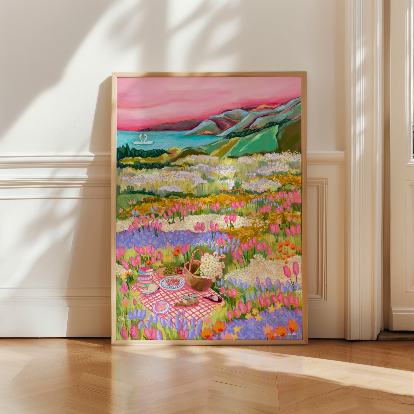 Colourful Illustration of wildflower fields with a picnic blanket, a basket of daisies and a few nibbles. In the background you can find the distant mountains and a lake where 2 swans sit. Designed by Rebecca Elizabeth Draws.
