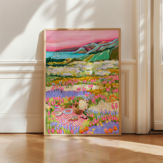 Colourful Illustration of wildflower fields with a picnic blanket, a basket of daisies and a few nibbles. In the background you can find the distant mountains and a lake where 2 swans sit. Designed by Rebecca Elizabeth Draws.
