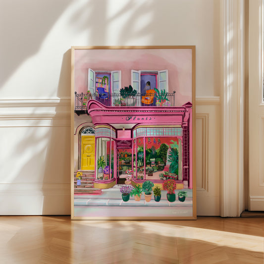 Pink shop front of a plant store with lots of greenery inside, a balcony above with windows showing chairs and a bookcase and more flowers. A yellow door to the side with a sunflower vase resting on the steps by Rebecca Elizabeth Draws.