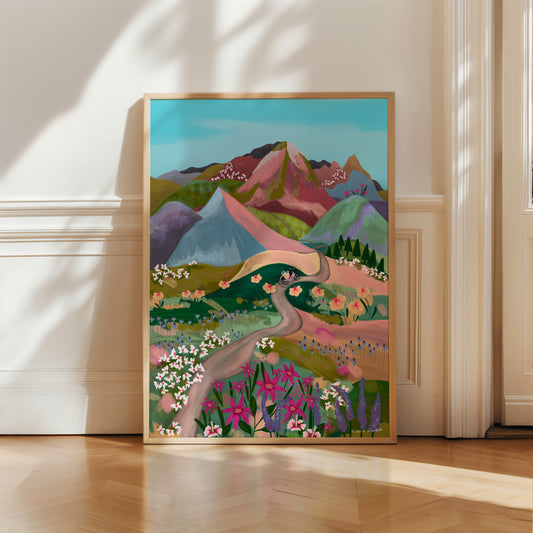 An illustration of a bike ride through the mountains. Fields of flowers in shades of green, pink, lilac, white and more. A winding path taken by the bicycle to the bottom of the mountains and then rolling mountains in lots of colours. These are muted but colourful rainbow mountains. There is a small signature in white the corner. Designed by Rebecca Gibbs at Rebecca Elizabeth Draws.