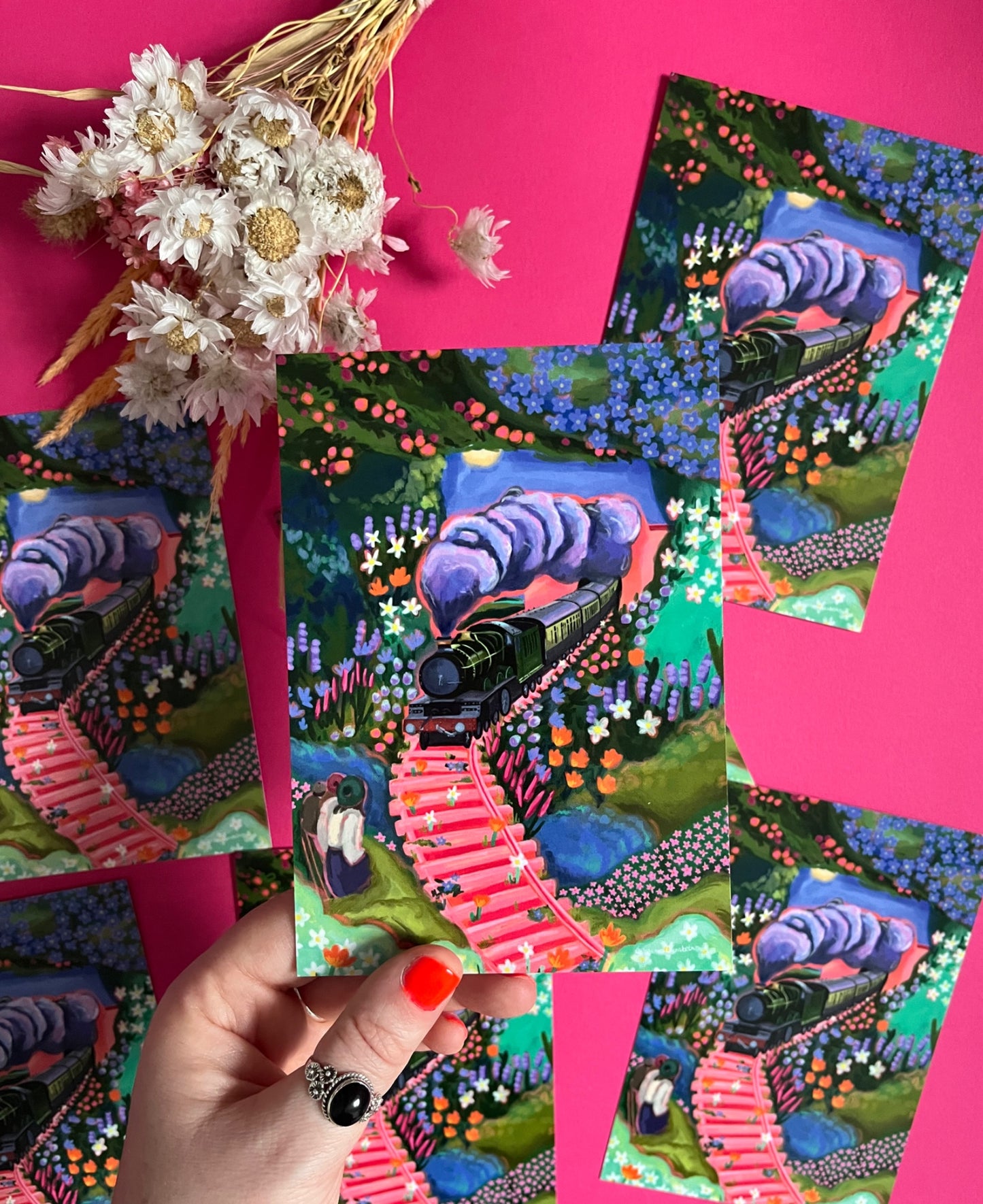 Postcard art inspired by the railway children book with a green steam train, three children watching with their backs turned and lots of overgrown flowers and plants. Designed by Rebecca Elizabeth Draws.Designed by Rebecca Elizabeth Draws.
