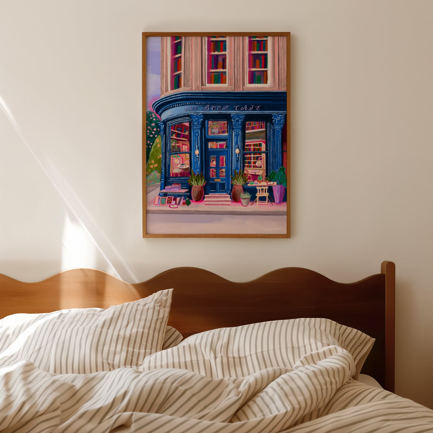 Store front illustration in a deep blue with antique vintage design, inside the book café is a bookcase with jewel tone books, a coffee stand with mugs & cake. The are tables inside and out and upstairs are 3 windows with shelves of books inside. Designed by Rebecca Elizabeth Draws.