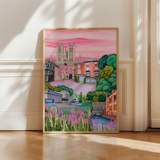 Lincoln, Lincolnshire UK. The cathedral is featured against a pink hazy sky, with the old tudor buildings to the left, the magna carta to the left and the top of steep hill. The bottom left features the quayside with boats and flowers and the right shows the tudor building hanging over the river into the city.