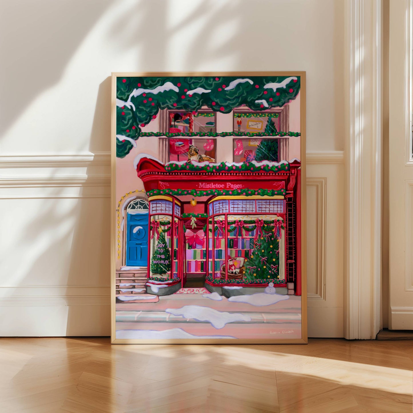 A Christmas bookshop store front illustration in red with soft whimsical colour books, festive decorations & a look upstairs inside the window at a cosy home with a dog. There is snow fallen around & a festive holly & berry tree hanging over the top