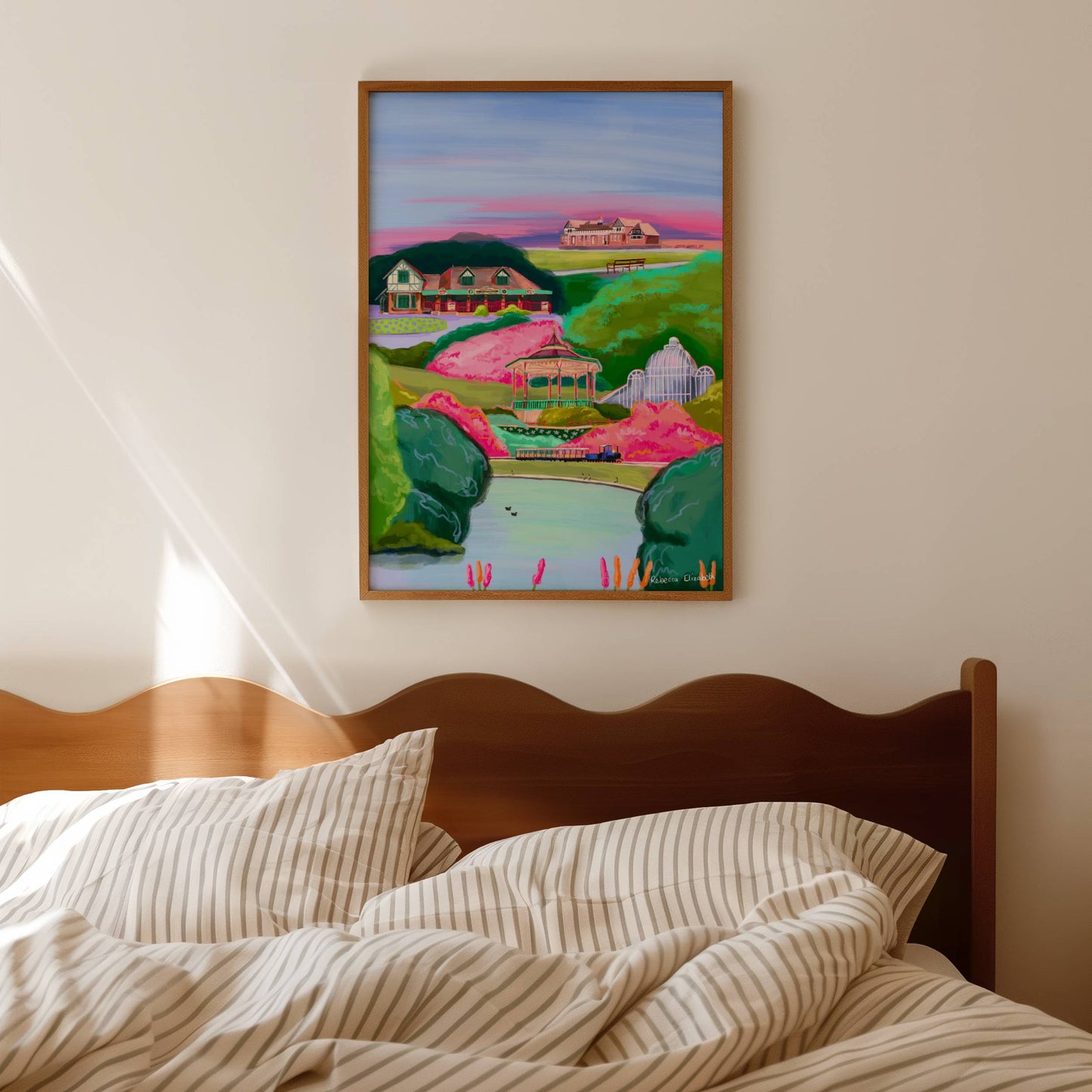 A vibrant and colourful illustration of Queens Park Chesterfield in Derbyshire. An illustration including queen’s parks pond, train, cricket building, glass building, café and more. Green trees and plants with vibrant pink blossom trees. There is a small signature in white the corner. Designed by Rebecca Gibbs at Rebecca Elizabeth Draws.