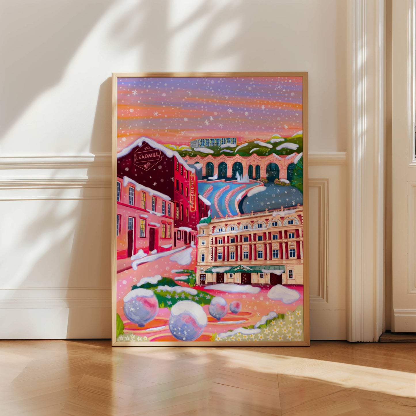 An illustration of Sheffield city in winter with snow. Featuring The Leadmill, the Lyceum, Sheffield train station, Sheffield Park Hill flats, park hill graffiti and water features. This illustration is very vibrant with bright pinks and oranges, the places featured are collaged together against a purple and orange sky. There is a small signature in white the corner. Designed by Rebecca Gibbs at Rebecca Elizabeth Draws.