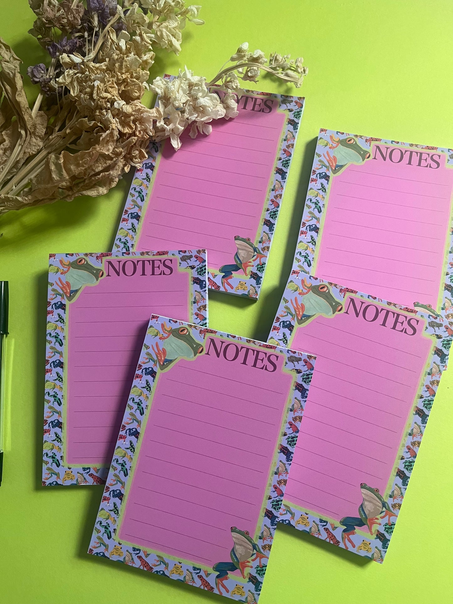 frog pattern notepad with purple background and a pink notes section. A couple of prominent frog’s peer around the notes. There is an accent colour of green, designed by Rebecca Elizabeth Draws.