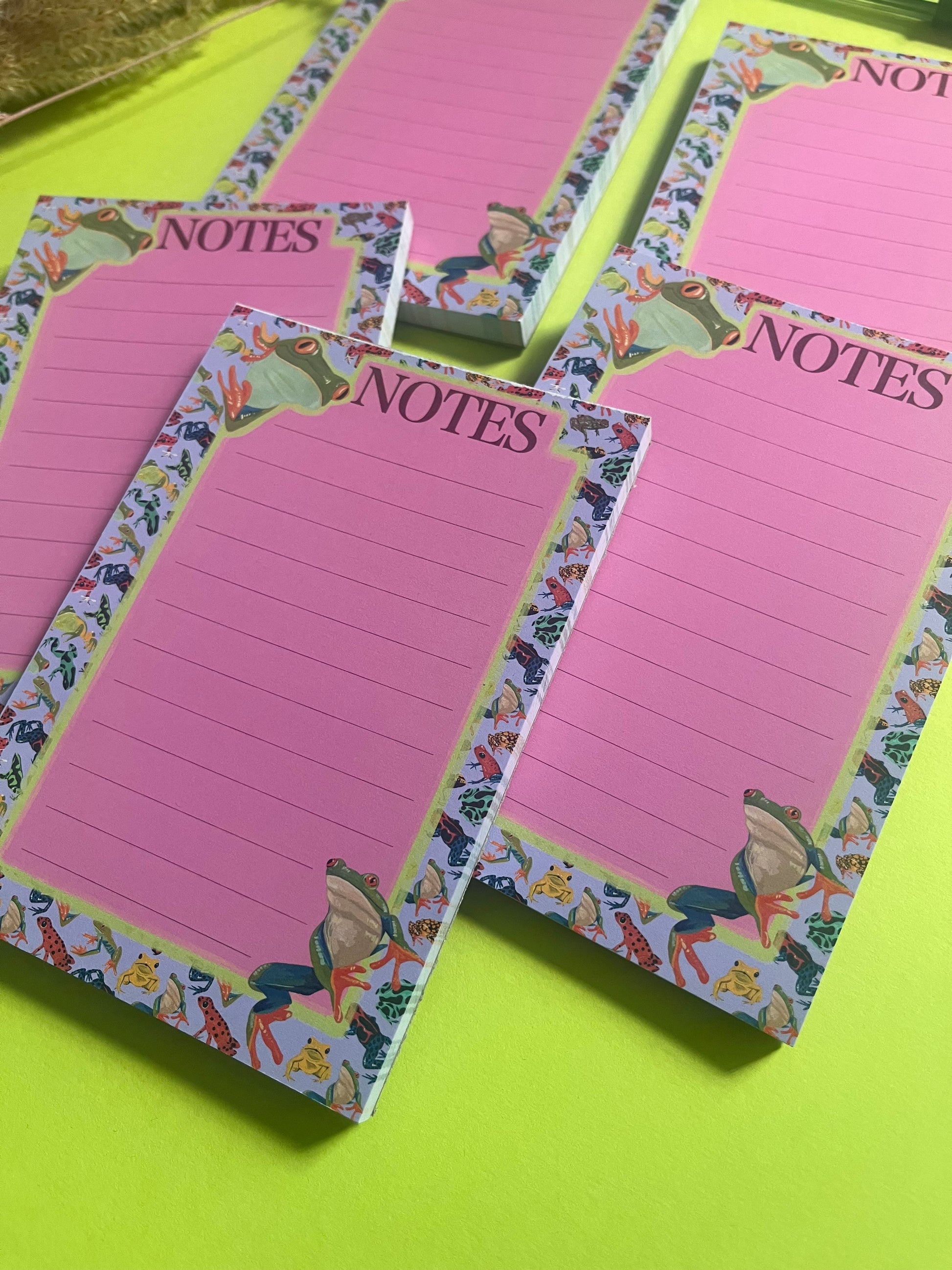 frog pattern notepad with purple background and a pink notes section. A couple of prominent frog’s peer around the notes. There is an accent colour of green, designed by Rebecca Elizabeth Draws.