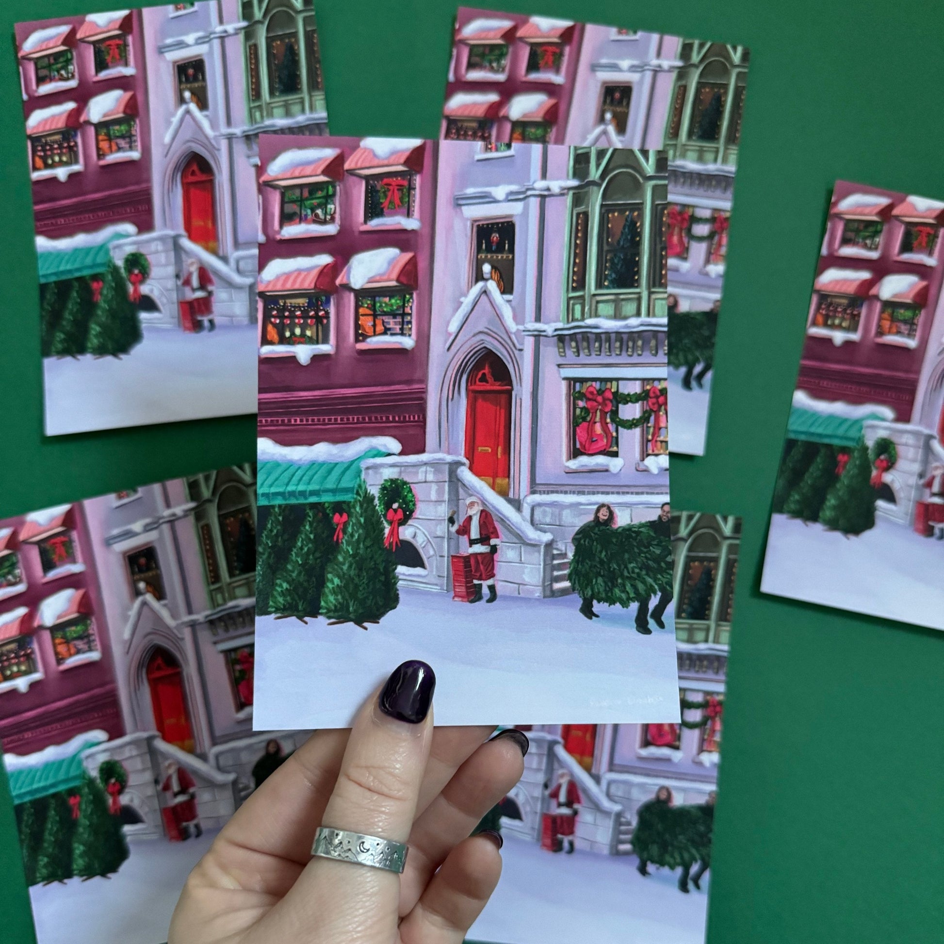 Christmas Illustrated postcard inspired by the film When Harry Met Sally. With Harry & Sally running off with their Christmas tree at the right hand side, the tree shop to the left and a background of new York buildings with Christmas décor peaking out the windows. Designed by Rebecca Gibbs at Rebecca Elizabeth Draws.