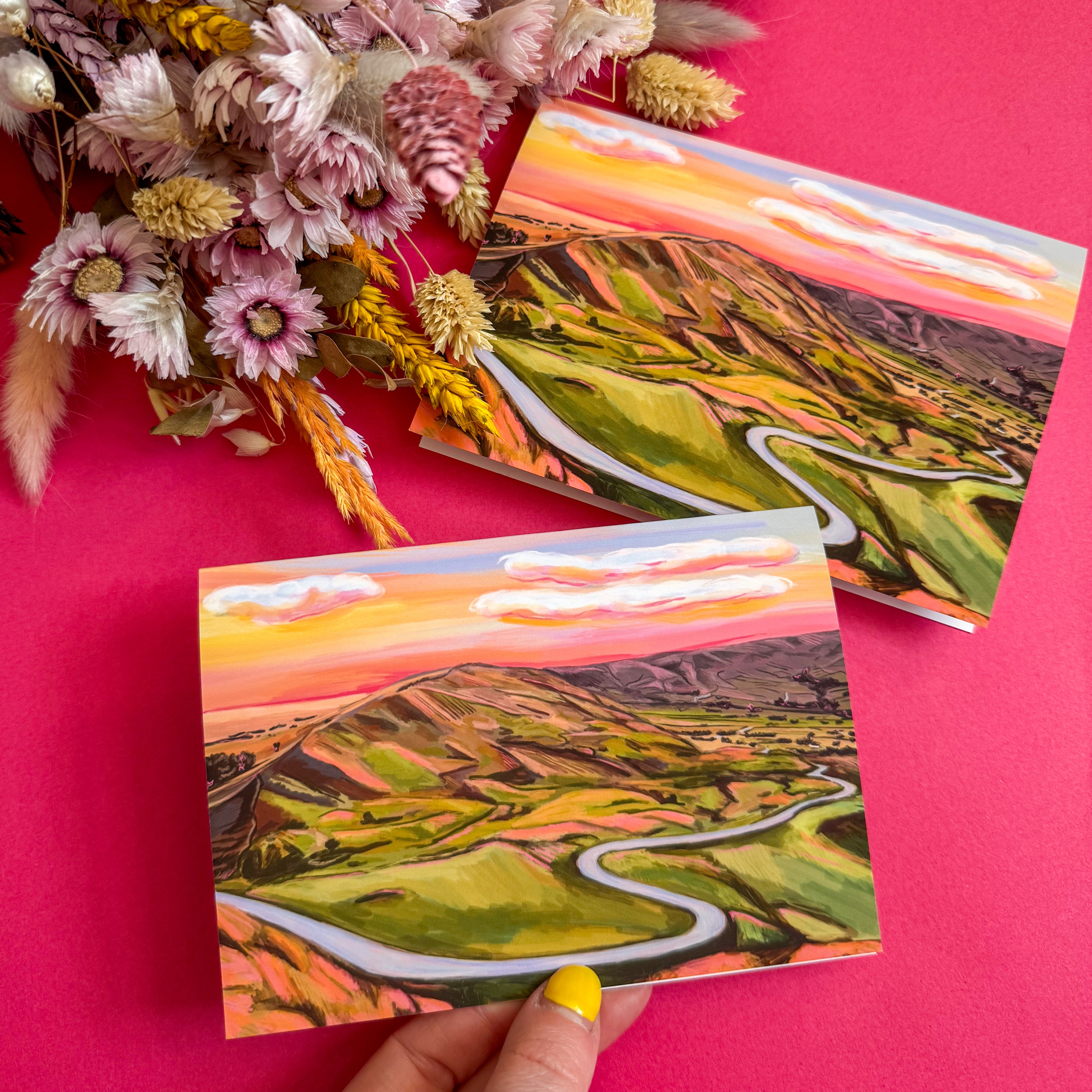 Postcards with mountain landscape design on a pink background with flowers.