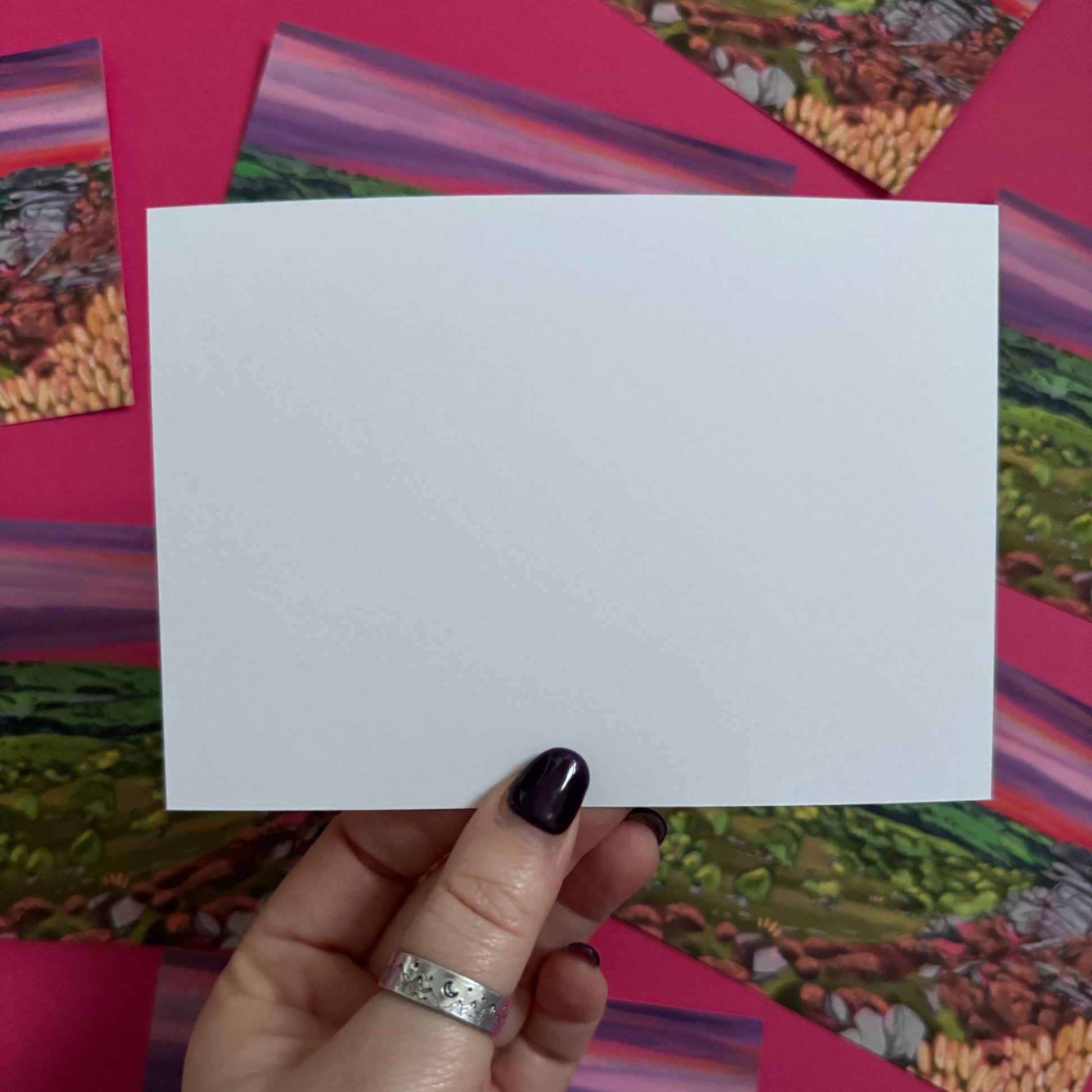 A colourful illustration of Curbar edge, Derbyshire with the rock formation to the right covered in pink and golden flowers, yellow flowers in the foreground and then rolling hills to the left with lots of greenery and trees. A stunning bright pink and purple sunset across the sky.  Designed by 
Rebecca Elizabeth draws. 
