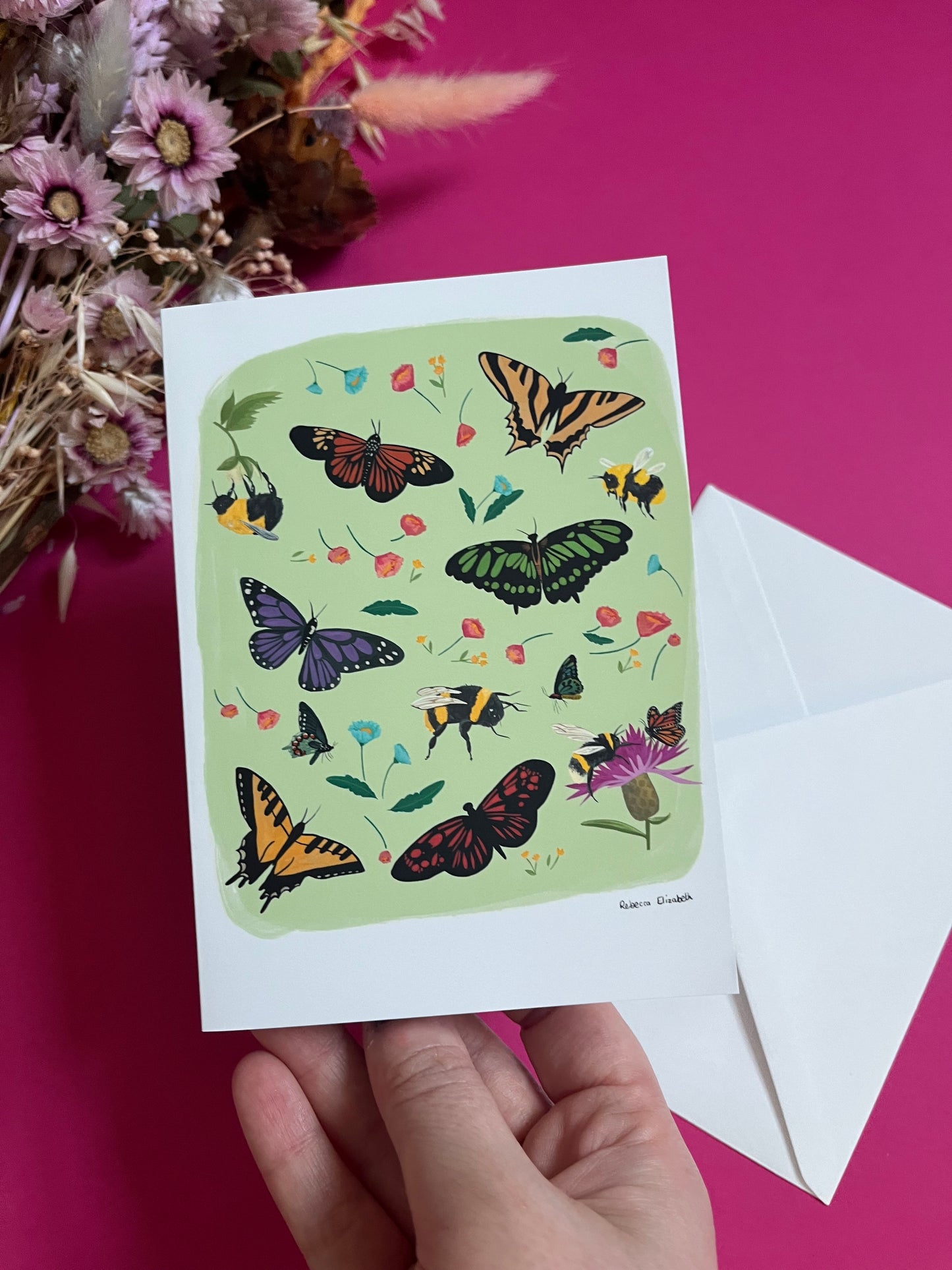 A collection of wildflowers, bumblebees and butterflies hand painted in gouache and edited digitally into a collaged design on a light green background. With a green back and the Rebecca Elizabeth Draws logo.  