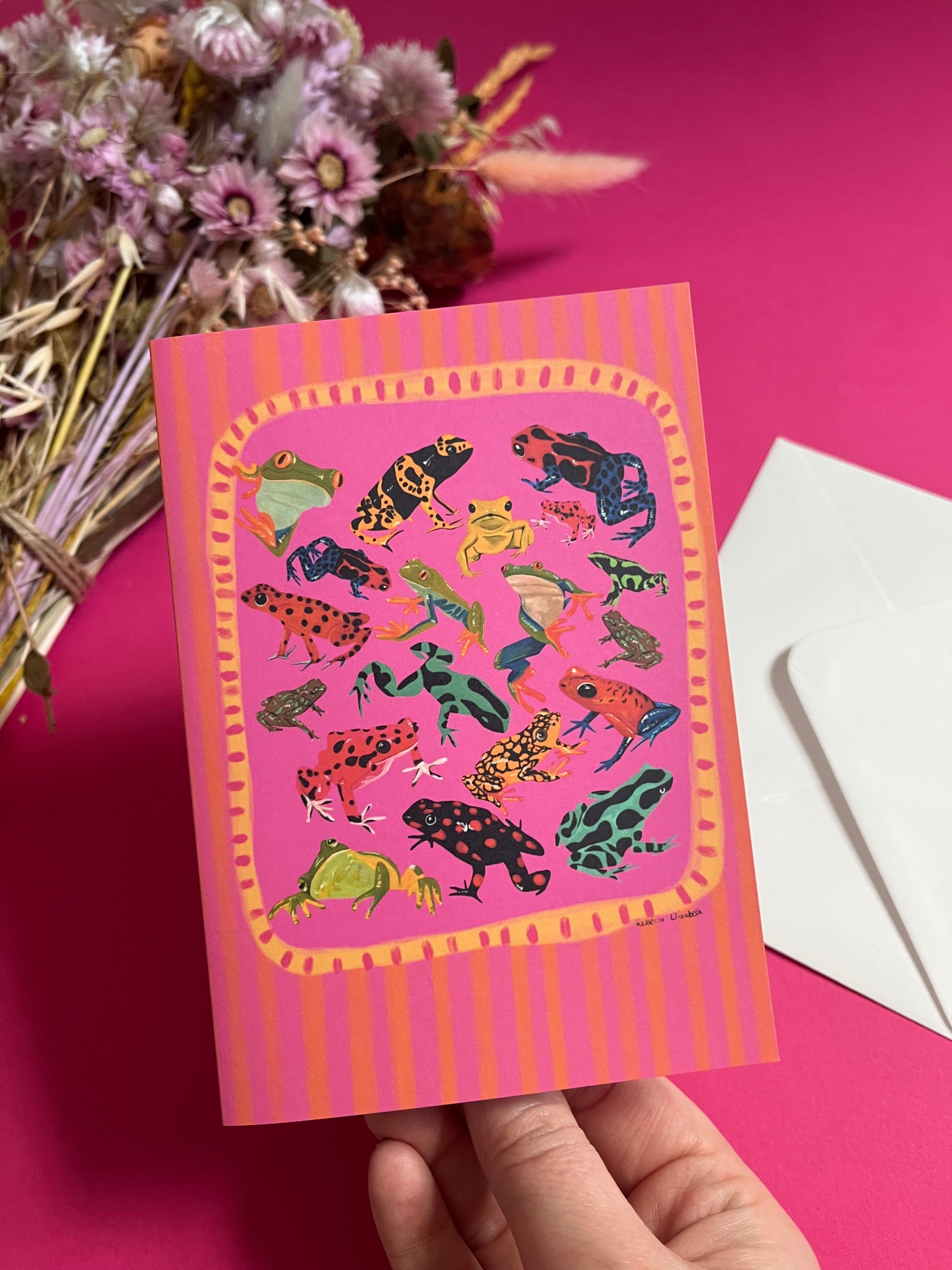 A collection of vibrant froggies to bring a pop of colour to your life. Hand painted rainforest frogs in gouache and edited digitally into a collaged design on a vibrant pink & red background. The back of the card has the Rebecca Elizabeth Draws logo