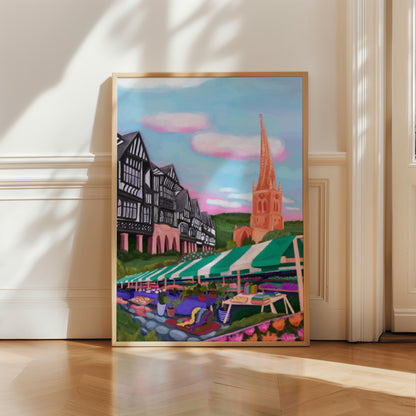 An illustration of the Derbyshire town Chesterfield. A summer illustration featuring the famous crooked spire, market stalls and Tudor buildings. Soft blue sky with fluffy clouds, this art piece is a soft representation of the market town. A small signature in white the corner.  Designed by Rebecca Gibbs at Rebecca Elizabeth Draws.