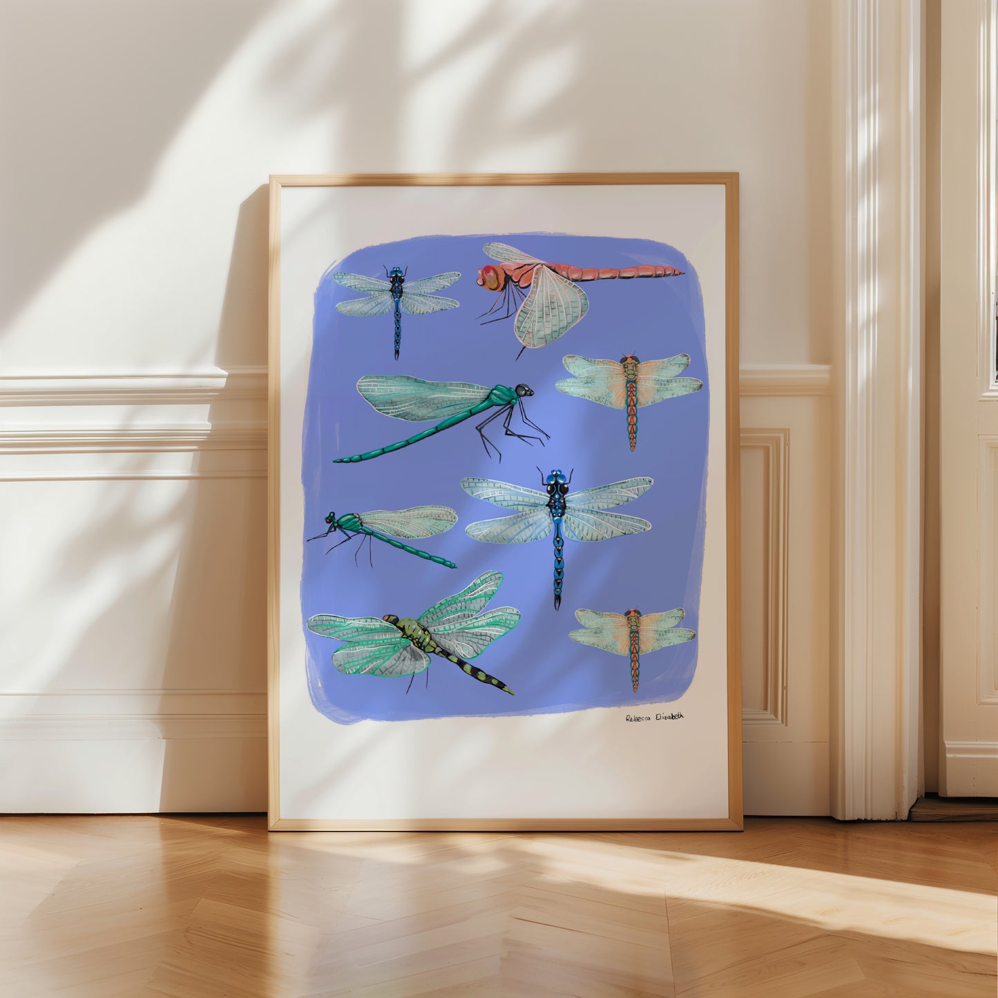 Hand painted dragonflies in gouache and edited digitally onto soft coloured blur backgrounds. Dragonflies in a flat lay composition with lots of intricate details featured. There is a small signature in black at the right.  Designed by Rebecca Gibbs at Rebecca Elizabeth Draws. 