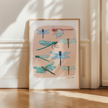 Hand painted dragonflies in gouache and edited digitally onto soft coloured cream backgrounds. Dragonflies in a flat lay composition with lots of intricate details featured. There is a small signature in black at the right.  Designed by Rebecca Gibbs at Rebecca Elizabeth Draws. 