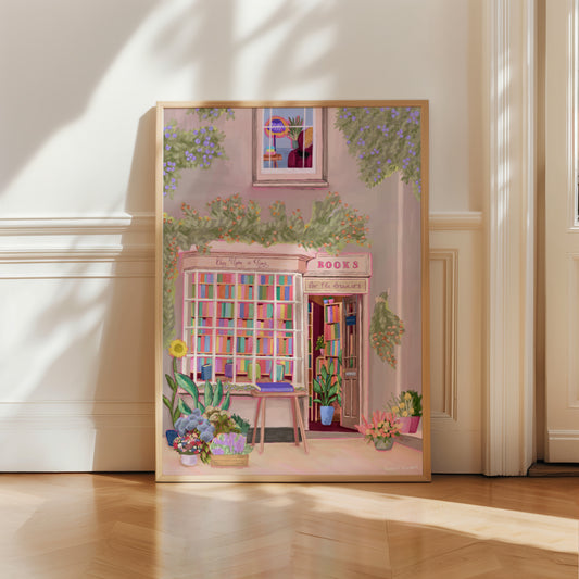 An illustration of a cute bookshop, the window shows the bookshelves inside full of bright coloured book spines. There are books placed stood up at the front. Outside the building is a soft colour with lots of greenery in soft pale greens and orange and lilac flowers. In front of the building there are plant pots and flowers. There is a small signature in white the corner.  Designed by Rebecca Gibbs at Rebecca Elizabeth Draws.