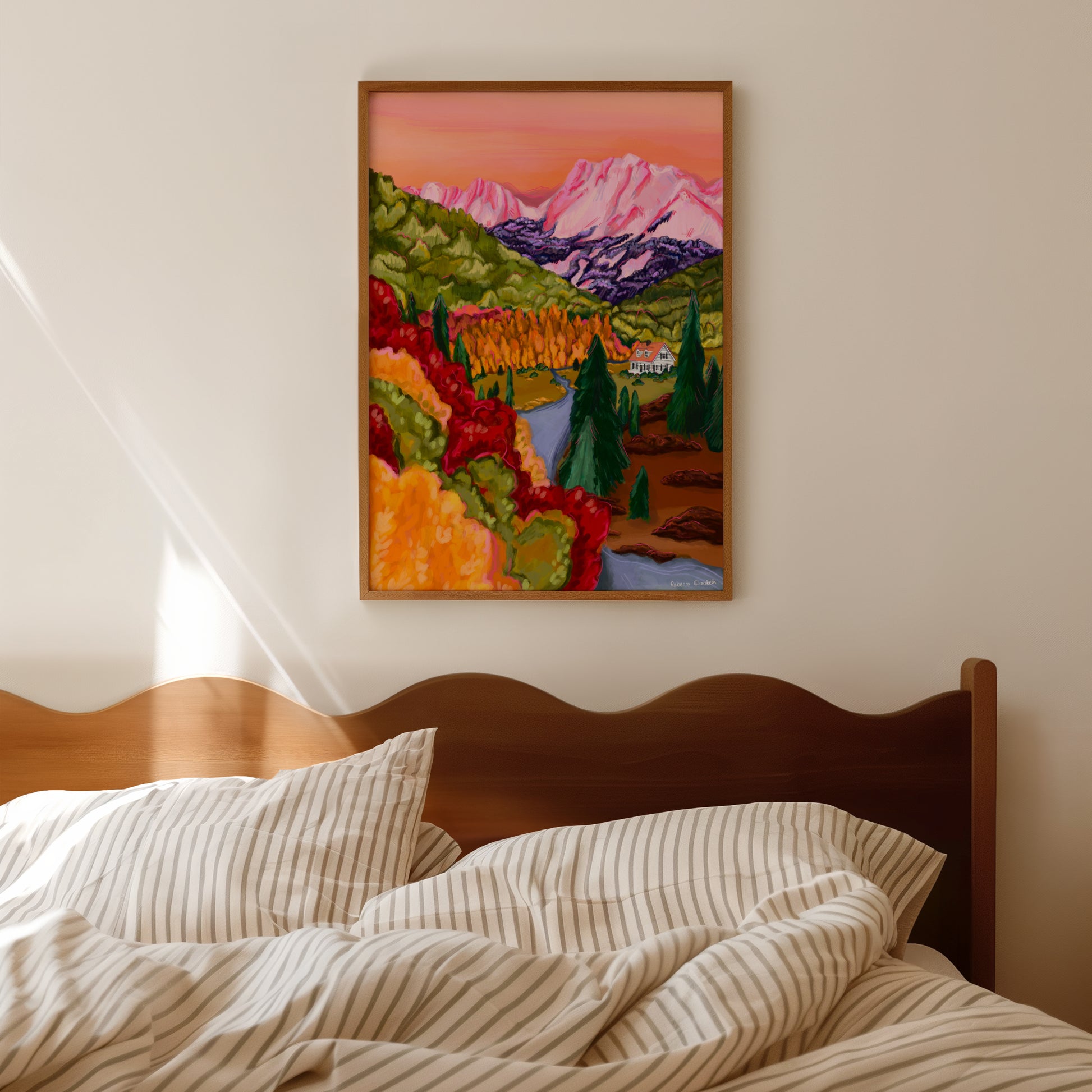 Pink, orange, red, brown and yellow mountain landscape illustration with autumnal trees and leaves. A cute cosy cabin sits nestled at the bottom of the mountains amongst the forest and a river runs alongside. Inspired by Colorado USA.