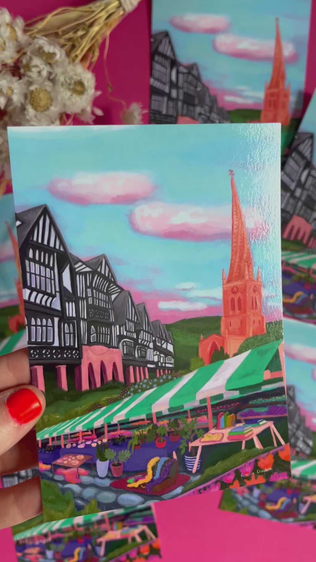 video of Postcard of an illustration of Chesterfield, Derbyshire town. Featuring the crooked spire, the Tudor buildings, the market, and the peak district hills. Set against a blue sky with fluffy white clouds. Designed by Rebecca Elizabeth Draws. 