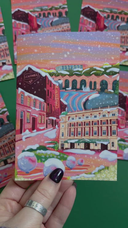 An illustrated greeting card of Sheffield city in winter with snow. Featuring The Leadmill, the Lyceum, Sheffield train station, Sheffield Park Hill flats, park hill graffiti and water features. This illustration is very vibrant with bright pinks and oranges, the places featured are collaged together against a purple and orange sky. There is a small signature in white the corner.  Designed by Rebecca Gibbs at Rebecca Elizabeth Draws.