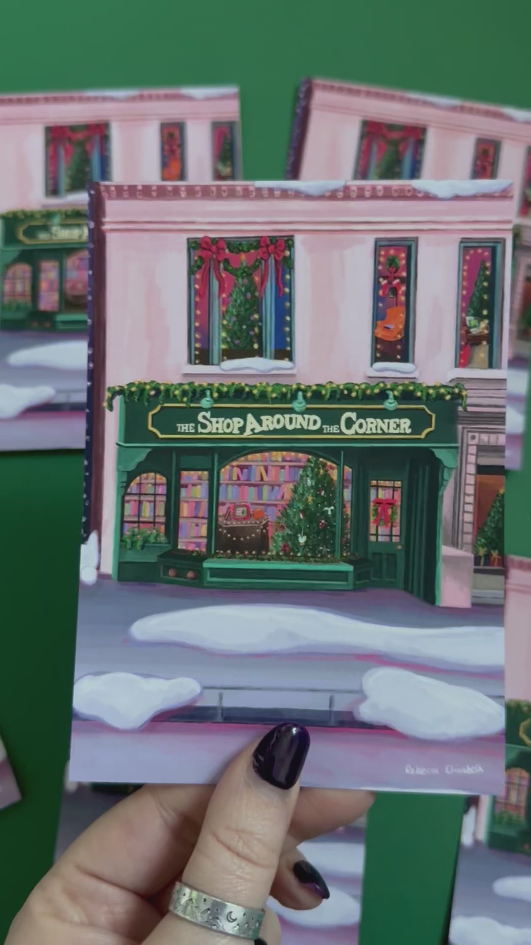 Christmas Illustrated postcard inspired by the film You’ve Got Mail. The Shop Around the Corner is a cosy & whimsical bookshop owned by Kathleen Kelly, inside is lots of fairy lights, Christmas trees, books and baubles. Outside you can see snow and inside the cosy windows with festive decor.  Designed by Rebecca Gibbs at Rebecca Elizabeth Draws.