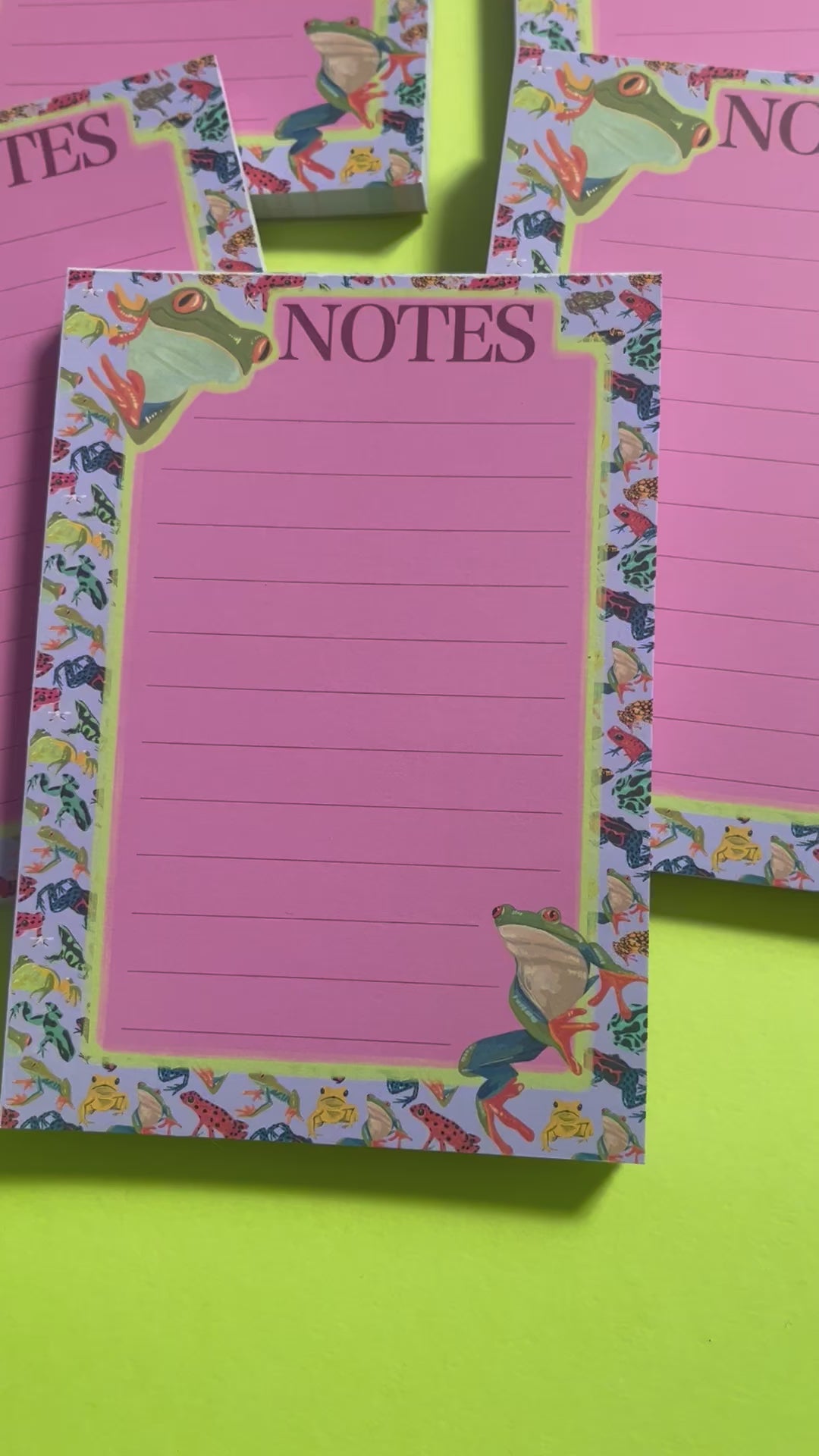 frog pattern notepad with purple background and a pink notes section. A couple of prominent frog’s peer around the notes. There is an accent colour of green, designed by Rebecca Elizabeth Draws.