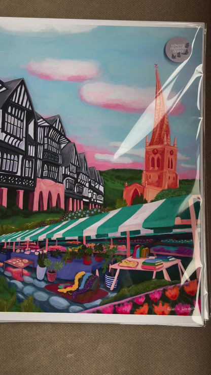 An illustration of the Derbyshire town Chesterfield. A summer illustration featuring the famous crooked spire, market stalls and Tudor buildings. Soft blue sky with fluffy clouds, this art piece is a soft representation of the market town. A small signature in white the corner.  Designed by Rebecca Gibbs at Rebecca Elizabeth Draws.