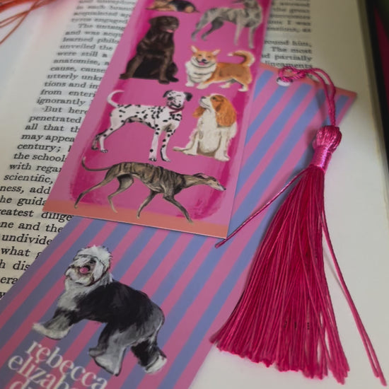 Hand drawn illustration of dogs, from whippets, lurchers, Labradors, Yorkshire terriers & more. All drawn in a collection on a pink background with pink and purple stripes on a bookmark with a pink & purple background & the Rebecca Elizabeth Draws logo. 