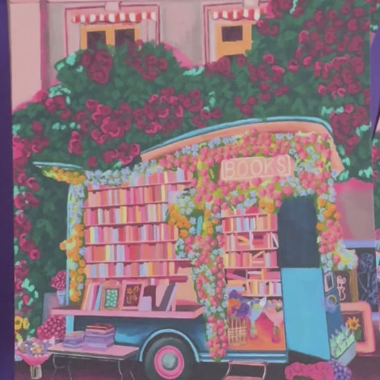 Illustration of a van opened up showing lots of bookshelves stacked with books, art frames out front and lots of blossoming pink, orange and blue flowers over the top. A big tree with pink roses over hangs and behind sits old fashioned buildings with quaint architecture and balconies. A whimsical fantasy print. 