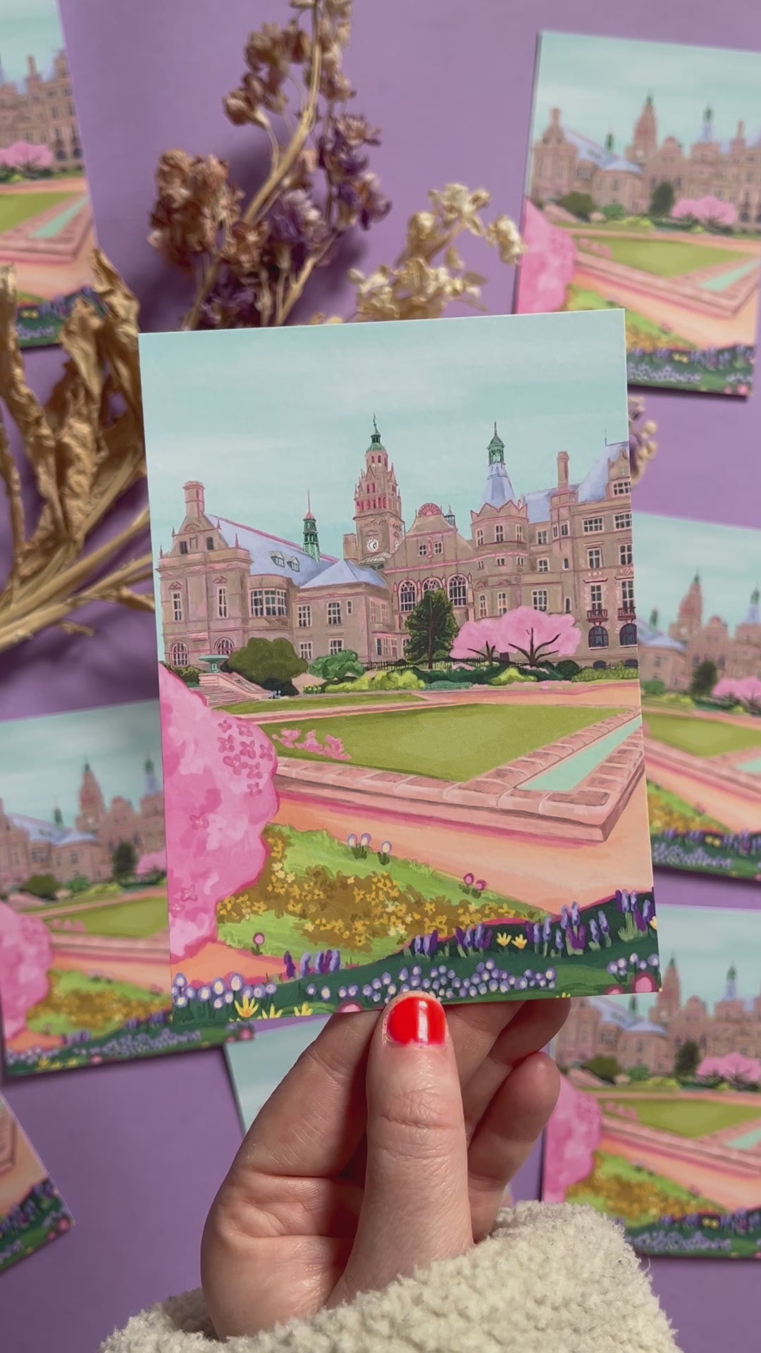 An illustration of the view of the Peace Gardens, Sheffield city centre in springtime. A soft brown building of Sheffield’s town hall with trees in front and pink blossom trees in soft pinks. The foreground features the peace garden with patches of grass and then flowers in yellows and purples underneath another pink blossom tree in the front and a baby blue sky. There is a small signature in white the corner.  Designed by Rebecca Gibbs on a postcard at Rebecca Elizabeth Draws.