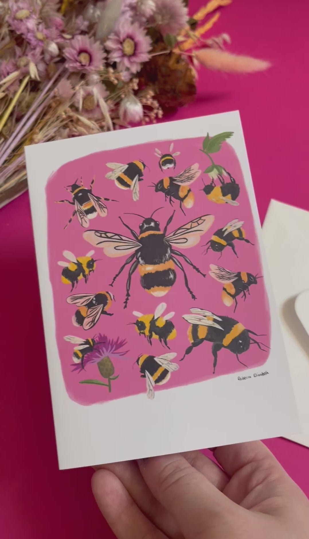 Hand painted bumble bee illustrations compiled together on a pink background, small bees big bees, bees with flowers. The back of the card is green with the Rebecca Elizabeth Draws logo