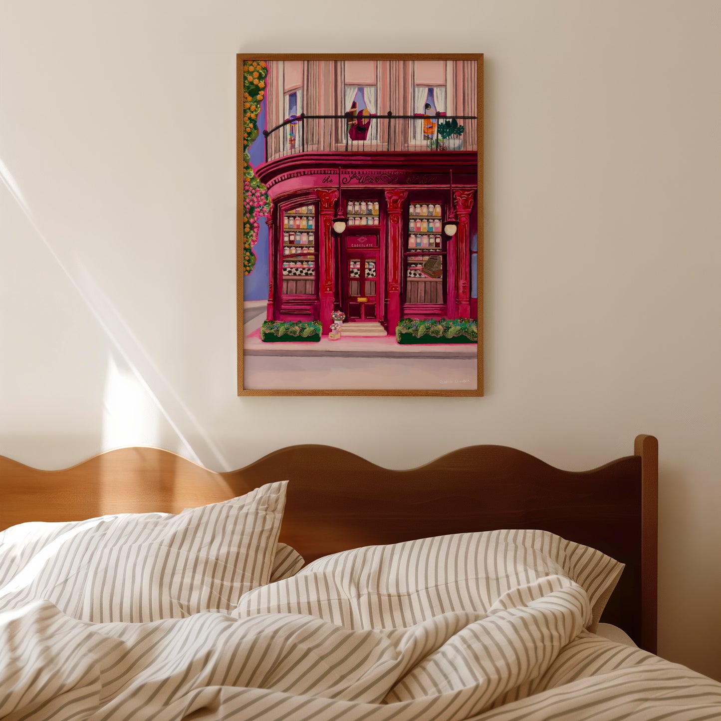 The sweet shop store front illustration. A red, burgundy, and pink toned shop front with ornate features, inside the window shelves of old-fashioned sweet jars filled with colourful candy. The countertop is black and white checker and a vintage till. The outside is surrounded by flowers. Designed by Rebecca Elizabeth Draws. 